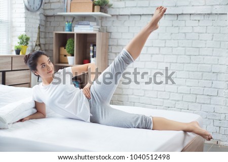 Asian women exercising in bed in the morning, she feels refreshed.She acts as squat. Royalty-Free Stock Photo #1040512498