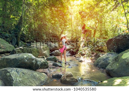 Asian traveler photographer women taking a photos of waterfall in deep forest in Thailand. Travel Concept.