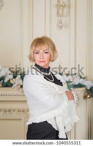 a good looking woman 50+ with short blonde hair looking into the camera, standing seriously folded her arms