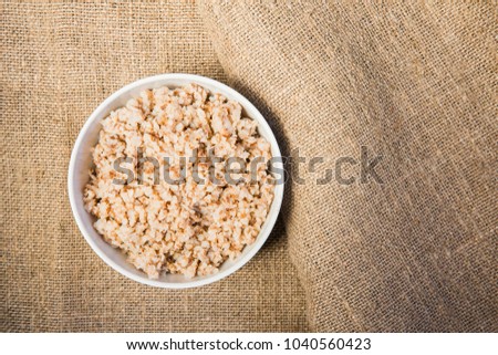 Buckwheat porridge in a white bowl on the tissue background
