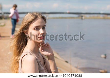Girl with blond hair on the promenade near river
