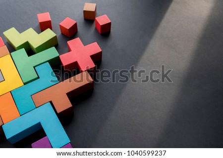 Different colorful shapes wooden blocks on black background, flat lay. Geometric shapes in different colors, top view. Concept of creative, logical thinking or problem solving. Copy space. Royalty-Free Stock Photo #1040599237