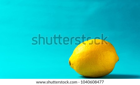 The one ripe yellow lemon on cyan blue background and copy space, summer concept picture