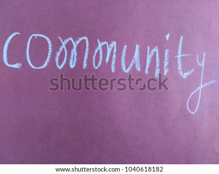 Text community hand written by white oil pastel on pink color paper