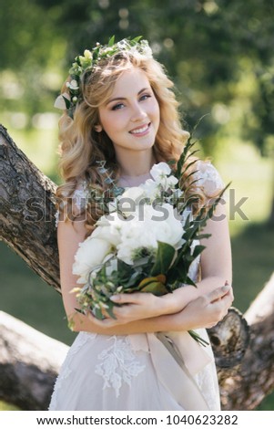 beautiful young bride holding wedding bouquet and smiling at camera