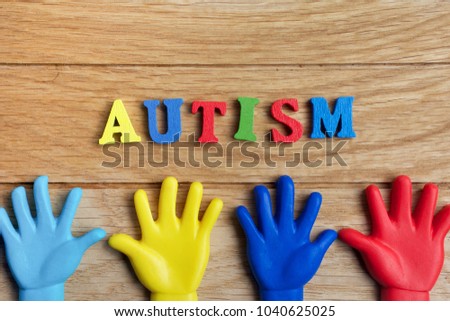 Autism awareness concept with colorful hands on wooden background. Top view