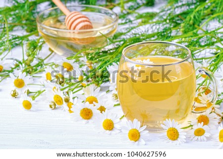 Cup of tea with chamomile flowers on a white wooden background(selective focus).