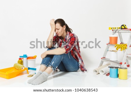 Confused annoyed tired sad upset woman sitting on floor with instruments for renovation apartment isolated on white background. Wallpaper accessories for gluing painting tools. Concept of repair home