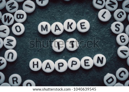 Motivation words MAKE IT HAPPEN made from small white letters on black stone background  