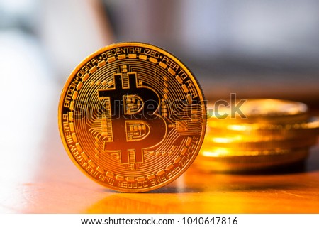 Bitcoin concept. Golden physical bitcoin in front of blurred laptop computer Cryptocurrency, online money in future business. Picture for add text message. Backdrop for design art work.