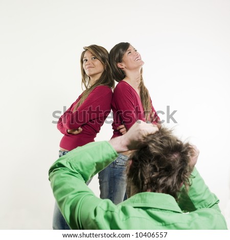 studio shot pictures on isolated background of two sisters twin women friends in front of a man tearing his hair away