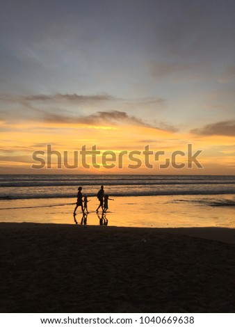 Romantic family walking by the tropical beach at sunset. Bali island, Indonesia