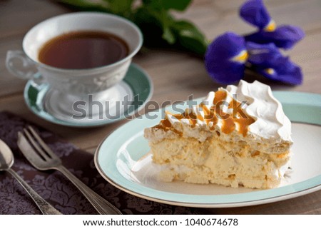 Slice of meringue cake and a cup of tea and iris