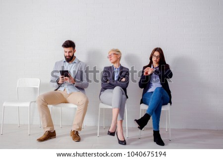 Two young woman and man waiting for job interwiev and looking very nervous