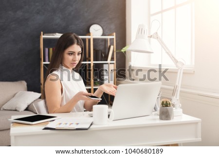 Young confused woman sitting at the table and working on laptop and having some troubles , copy space