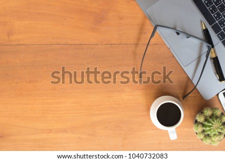 Office desk table with pen, glasses, keyboard on notebook, coffee and cactus. Top view with copy space.