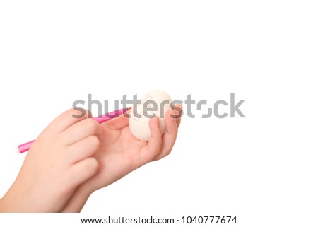 Girl's hand draws a Christian cross on a white chicken egg. Pink felt-tip pen in the child's fingers. Traditional symbol of Easter. Kid's hobby on the eve of Spring holiday. Isolated photo clipart.