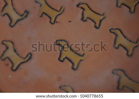 Close-up of a glazed ceramic surface. Handmade ceramic plate with yellow dog print.
