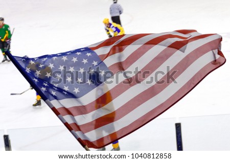 USA flag waving against a defocused hockey game background.