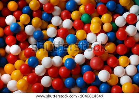 Multi-colored balls, round, plastic, red, white yellow, blue, in a dry pool.