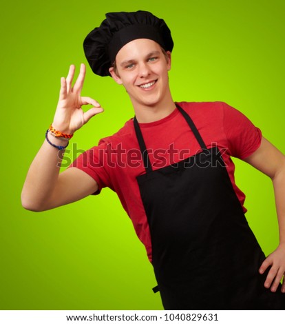 male chef showing ok hand sign isolated on green background