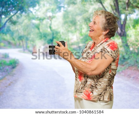 Senior Woman Holding  Camera, Outdoors