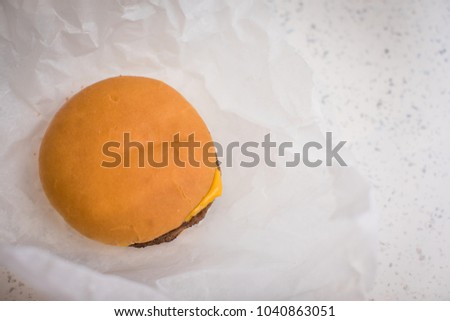 Cheese burger sat on a counter top in grease proof paper Royalty-Free Stock Photo #1040863051