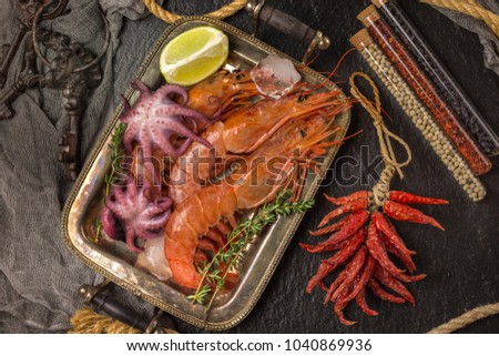 Fresh seafood shrimps octopus and squid On a vintage old tray. Decorated with lemons, herbs, spices and ice. Top view.