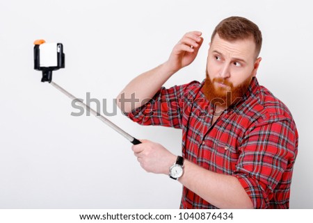 man with red beard in plaid shirt makes selfie on phone