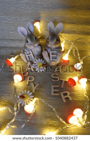 Two Rabbits, flowers, lighting Toadstools and Inscription Happy Easter from wood Letters