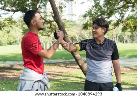 Friend of greeting the morning with holding hands after running exercise. Two man athletic friends greeting each other with arm wrestling in the park. Concept friendship 