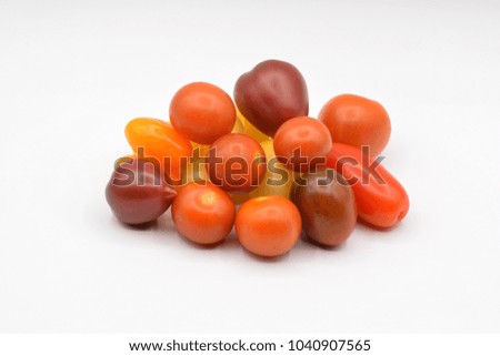 Colorful tiny grape tomatoes arranged on a seamless white background. 