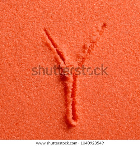 Letter Y written on orange sand.