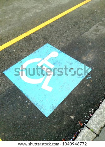 Blue sign painted on the asphalt of a parking reserved for people with disability