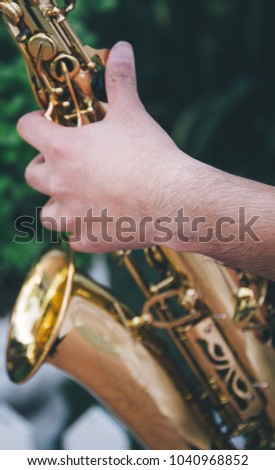elective focus.hands saxophonist playing saxophone on yellow wall background .concept for instrument musician,world Jazz festival,musical background.copy space for text