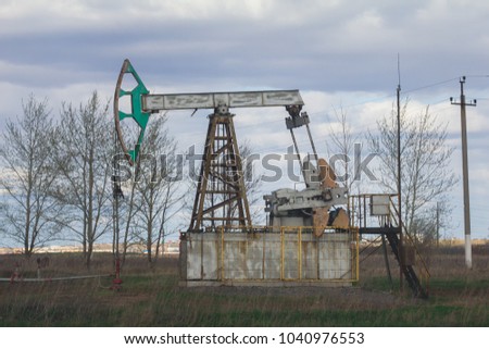 Oil pumpjack among grassy field at sunny day