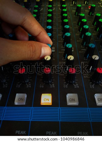 Close Up Man Hand Controlling Audio Mixer, with yellow Light Flare Effect