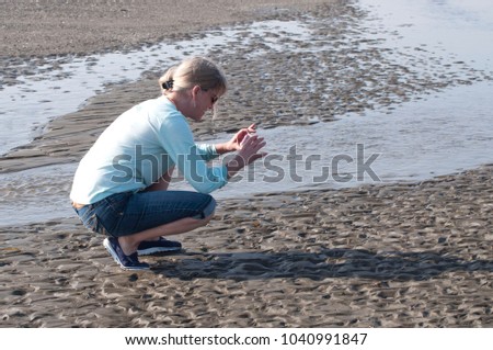 Adult female tourist taking photos on the shore on the beach on the Pacific Ocean at Twin Harbors State Park in West Port, WA, USA.