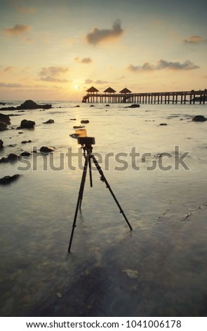 Smartphone on tripod capturing seascape sunrise time lapse. Mobile photography concept.