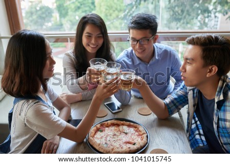Group of young VIetmnamese people drinking beer and eating pizza in cafe
