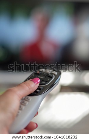Closeup of woman holding remote watching TV