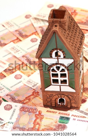 a pile of Russian paper rubles and a house as an illustration of a mortgage