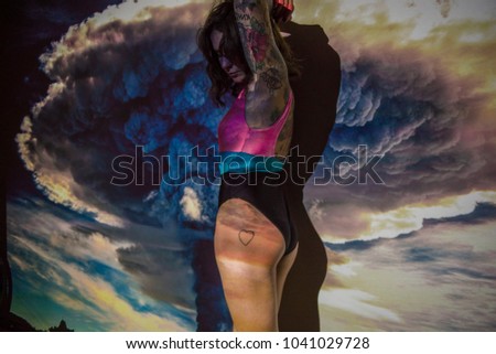 The image of huge storm is projected on a young woman in swimsuit.