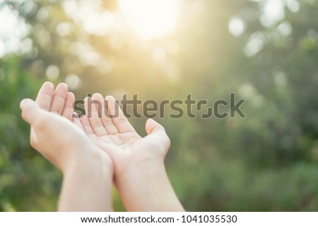 Woman open hand up to sunset sky and green blur leaf bokeh sun light abstract background. Vintage tone filter effect color style.