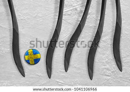 The Swedish puck and five sticks on the ice of the hockey arena. Concept, hockey