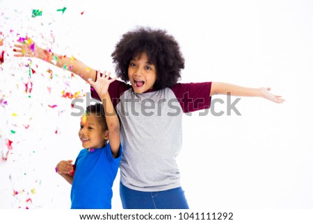 African American children smiling with happiness throwing colorful confetti. Friendship, siblings, celebration concept