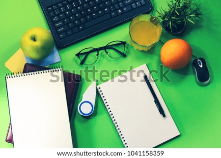 office working table. flat view from above. keyboard, notebook, stationery, orange, juice, apple.