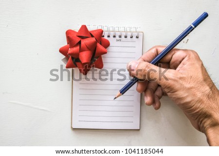 man writing notepad gift box and pencil on desk wood  background.using wallpaper for education, business photo.Take note of the product for book with paper and concept, object or copy space
