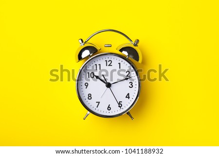 Retro alarm clock on bright yellow background