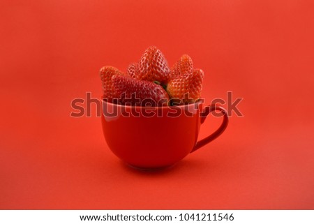 Strawberries in a red mug stock images. Strawberries on a red background. Red cup with strawberries
